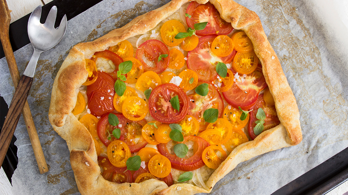 Pizza med röda och gula tomater och uppvikta kanter.