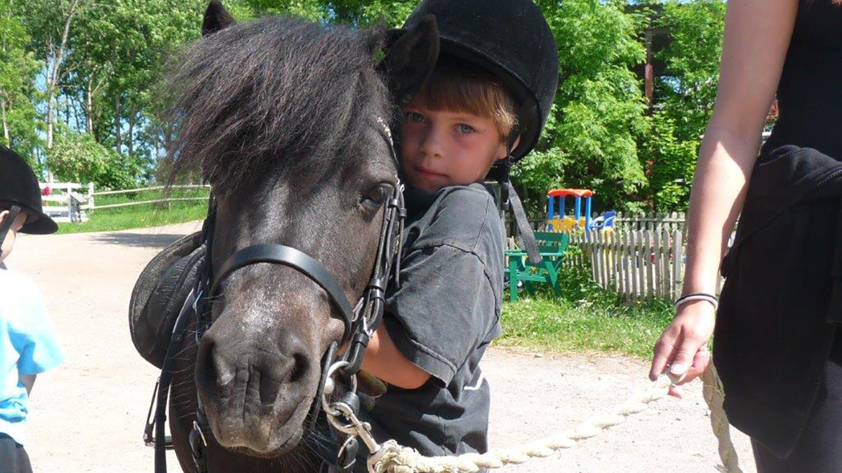 Ett barn som kramar en svart häst