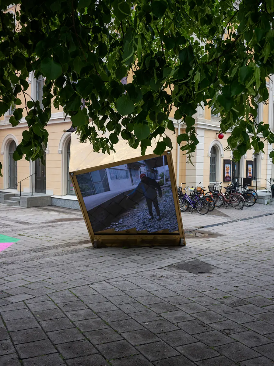 En snedställd kub med en video på ena sidan är placerad i stadsmiljö