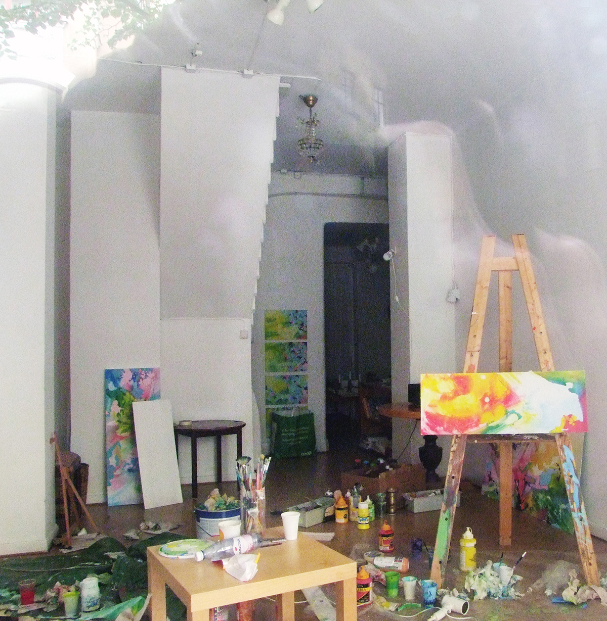 En ateljé i kaos målarfärgstuber står överallt på golvet och penslarna ligger utspritt. 