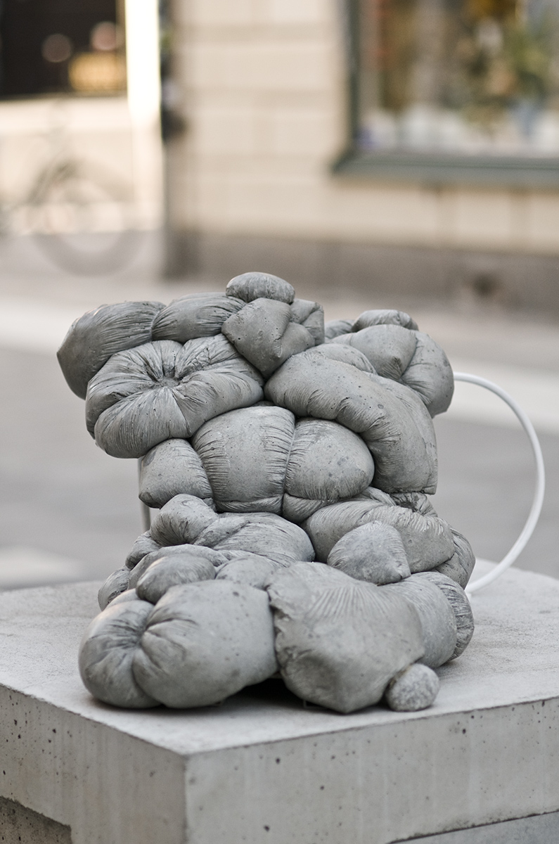 En betong skulptur som liknar fyllda plastpåsar i betong samlade på varandra. 