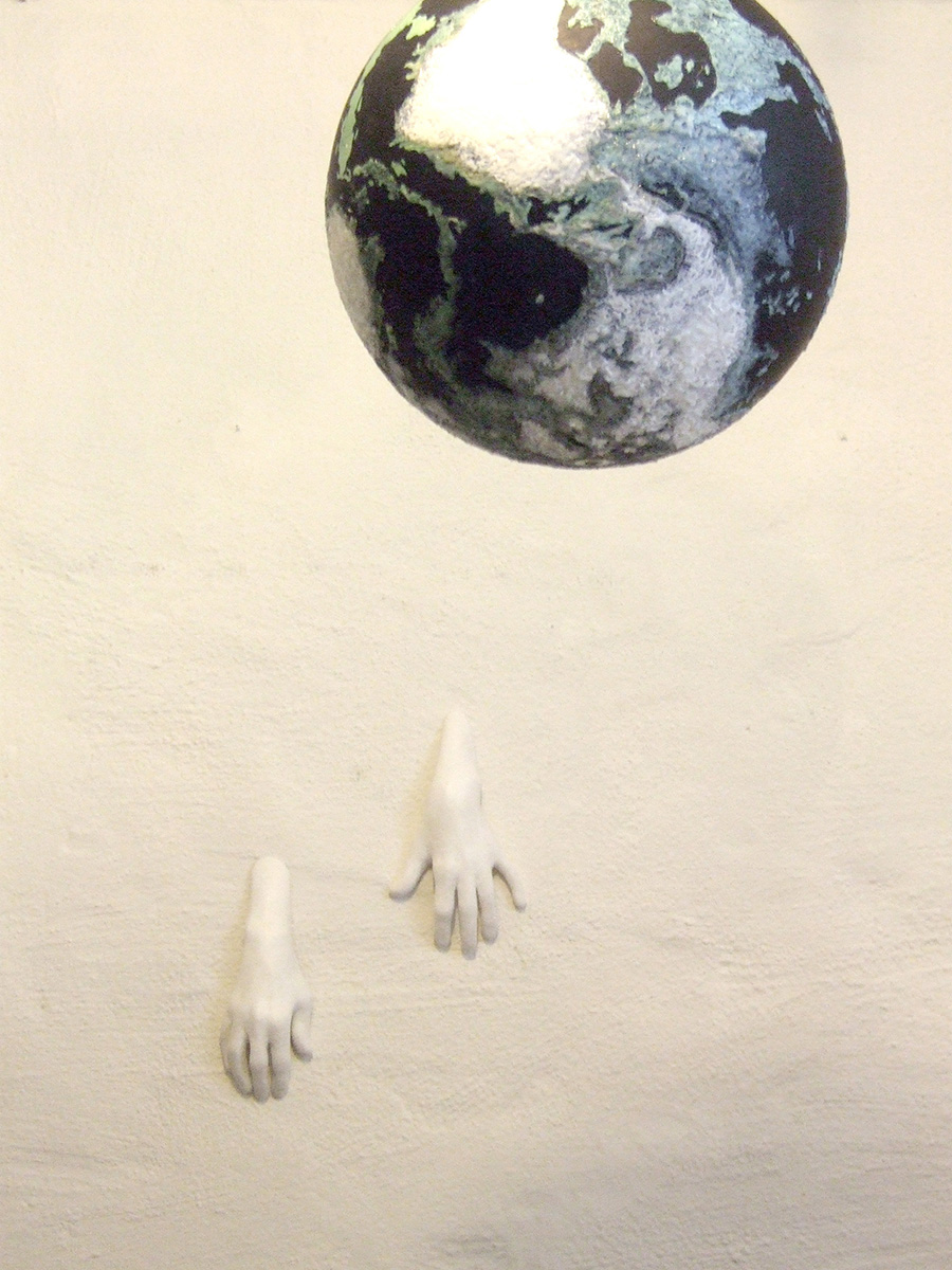 Ur en vitt vägg sträcker sig två små händer ut och ett jordklot. 