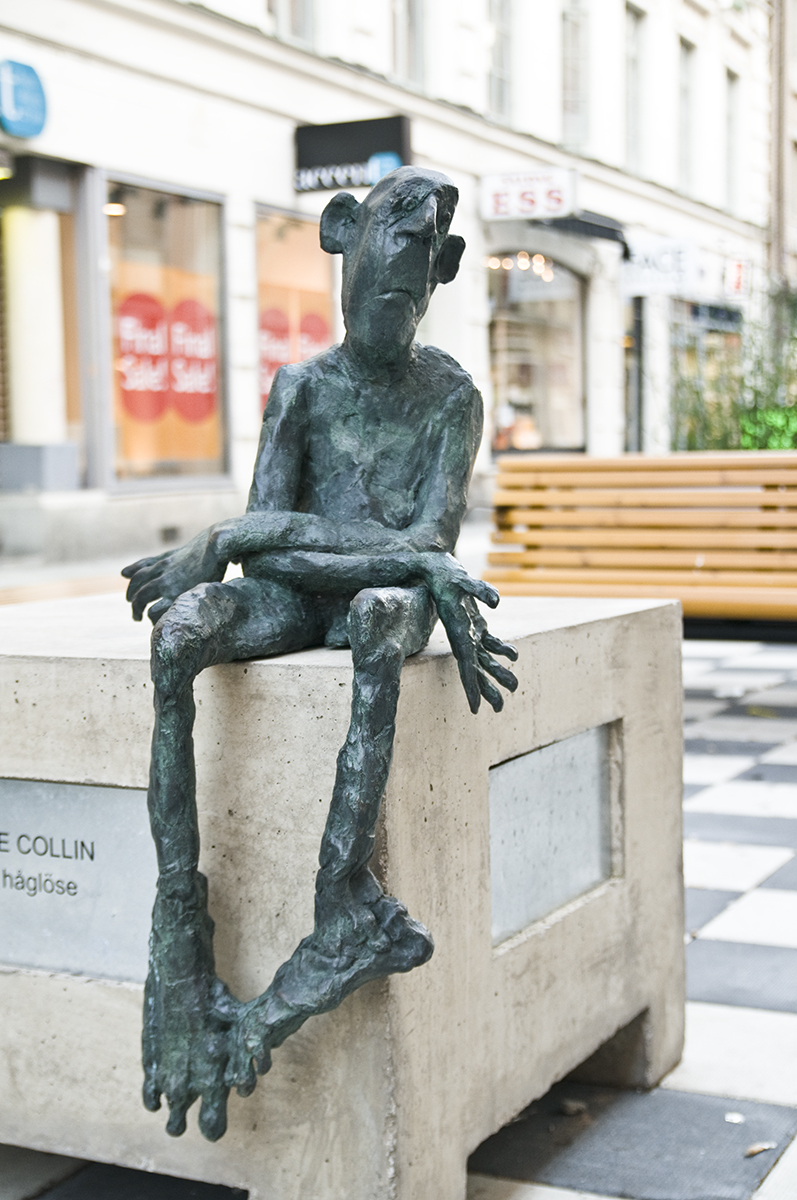 På ett betong bord sitter en liten staty av en vanställd man.