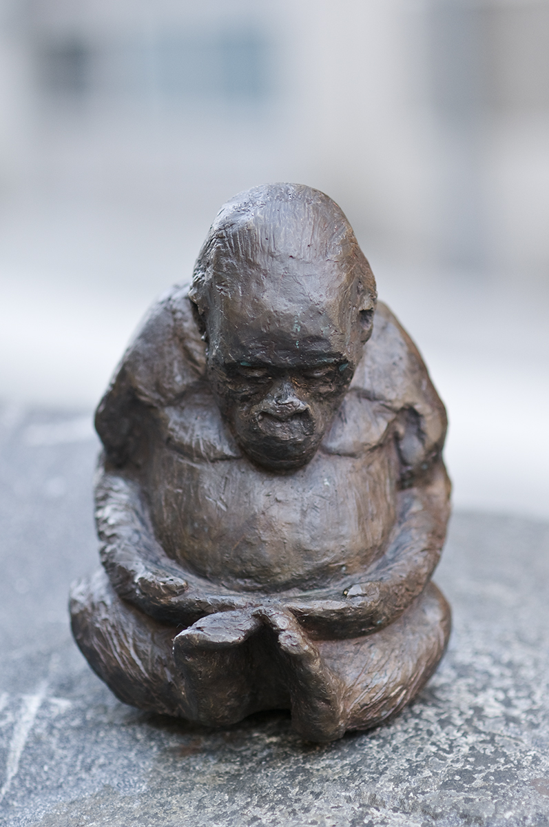 En ler skulptur av Kolmårdens gorillapojke Enzor när han var ett år och två månader gammal. Enzor ser i sina händer och fascineras av att vara till. Man känner igen detta i barn som gör samma sak. 