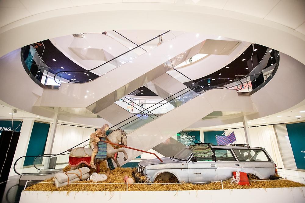 In a shopping mall, the sculpture is placed, right under the escalators. It is an old scrap car and a rider on a horse, the rider has impaled the car with his lance.