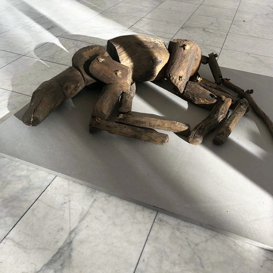 En träskulptur i form av ett djur ligger på golvet. Den har ledade kroppsdelar som en marionettdocka.