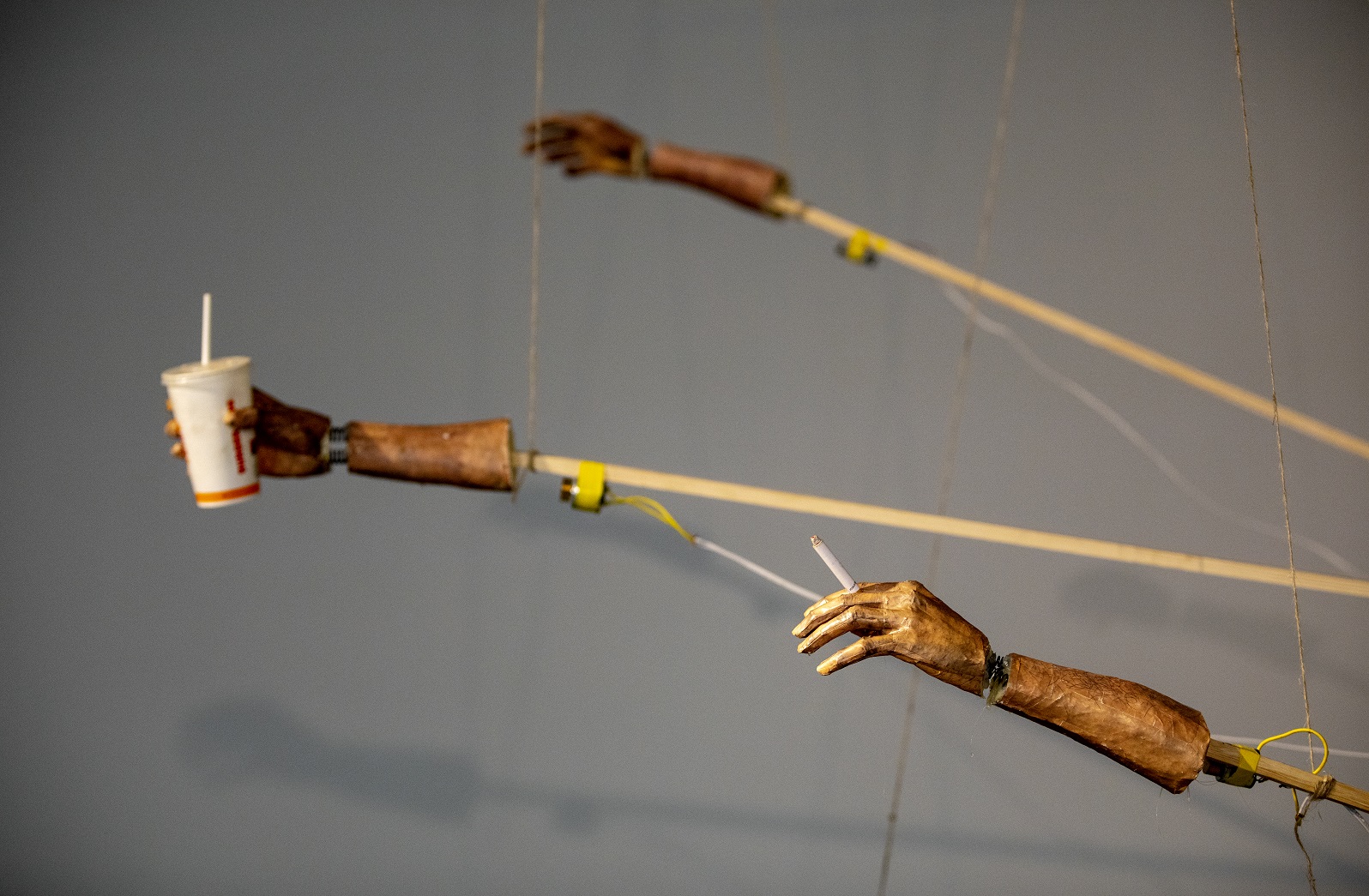 Arms that extend and move mechanically with the help of strings. The arms are made of sticks but have realistic hands. One hand holds a Burger King mug and two others holds cigarettes.