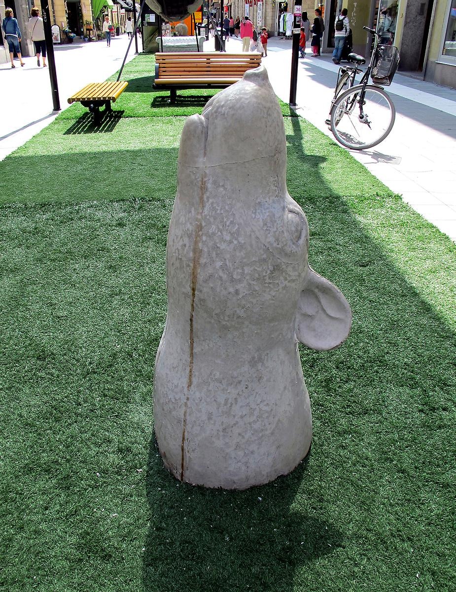 På en konstgjord gräsmatta längs Kungsgatan sticker en skulptur upp av ett råttansikte i betong. 