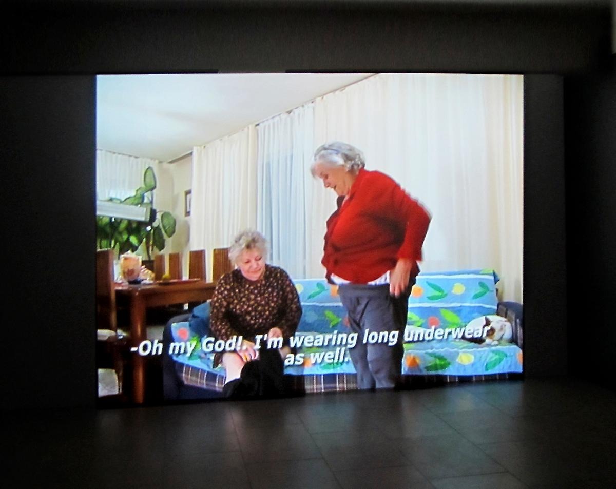 På en projektor skärm syns två kvinnor som har en konversation.