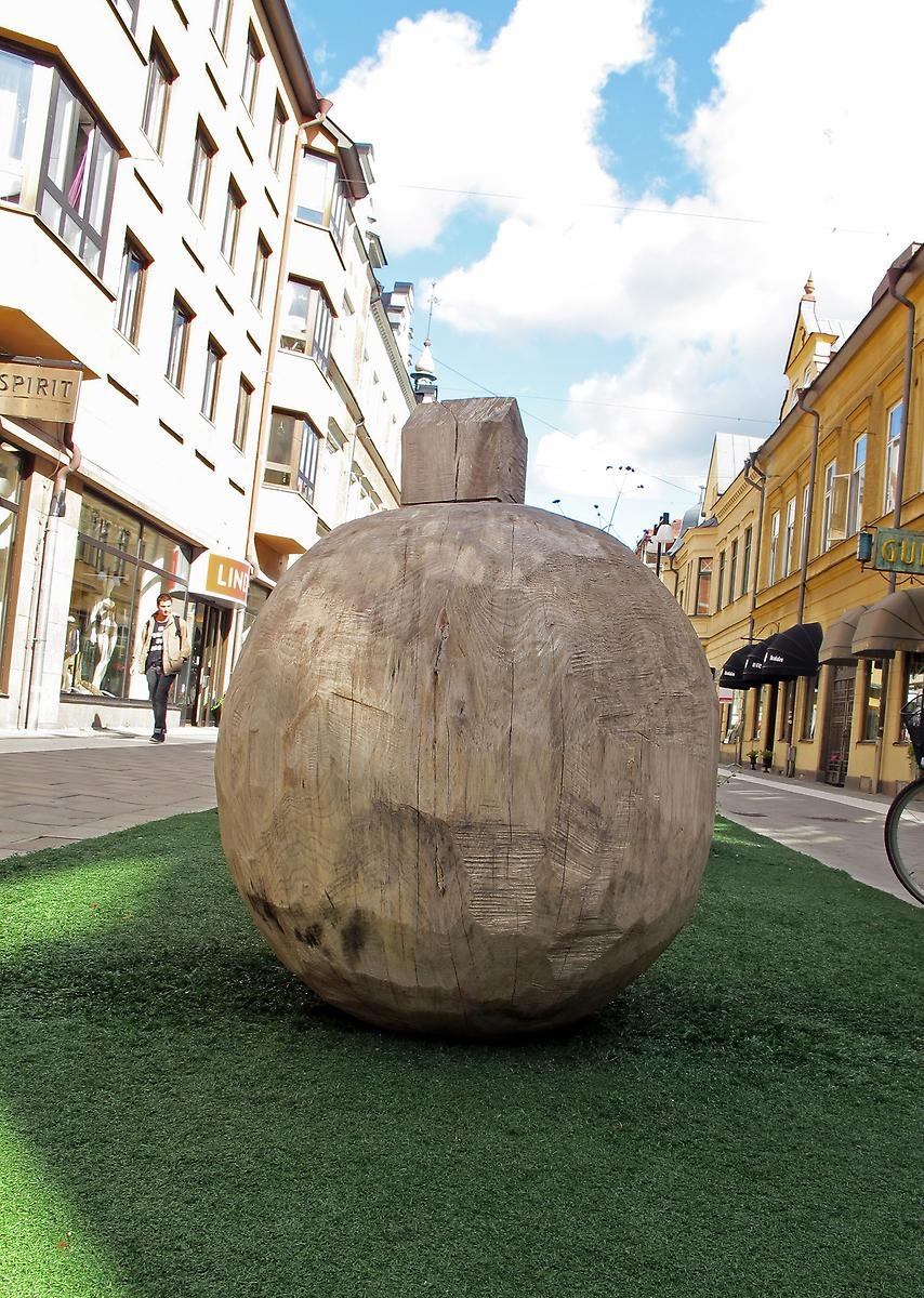 I mitten av hela Kungsgatan har en avlång gräsmatta rullats ut. Framför butiken LINDEX står en trä skulptur formad som en rund flaska.