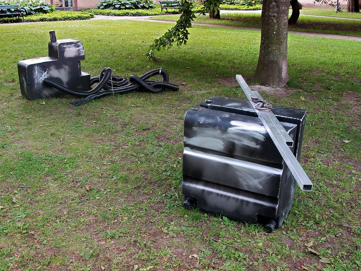 Utomhus på en gräsmatta står två aluminium klumpar som liknar två generatorer.  