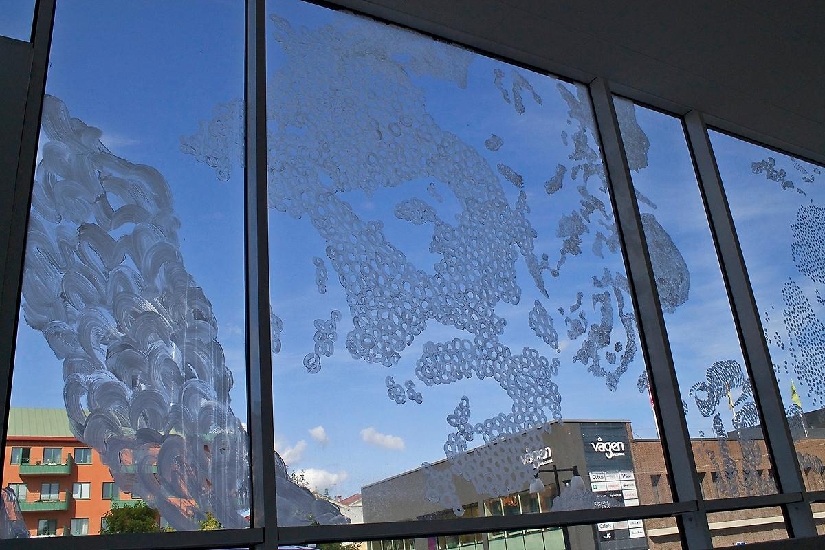På ett stort glasfönster har konstnären målat mönster med yoghurt.