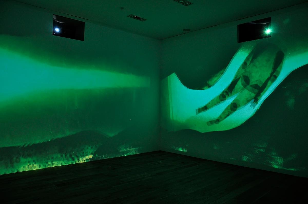 I ett mörkt rum är väggarna fyllda med en animation av en flod där ryggradslösa figurer flytter runt.