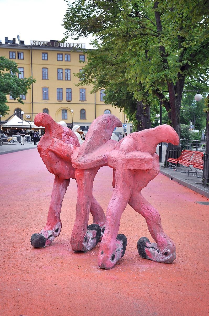 På en orangegata står en skulptur bestående av fem flamingohuvuden ihopsatta. 