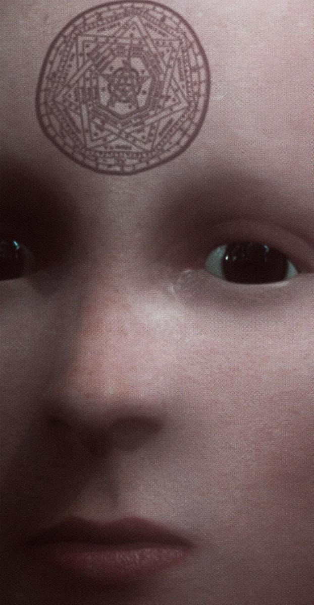En närbild på en människa utan ögonbryn och ögonfransar. I personens panna sitter en tatuering föreställandes en sjuuddig stjärna som är inringad. 