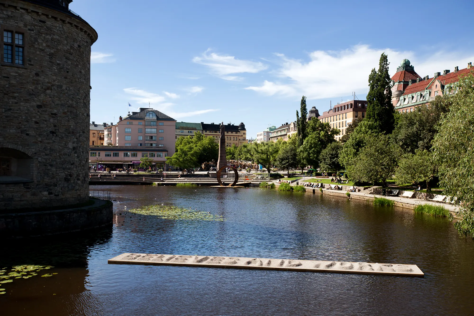 I vattnet framför Örebro slott ligger en stor rektangulär plattform. På plattformen står stor text som börjar med  ordet "BELIEVES" skriven i sand.