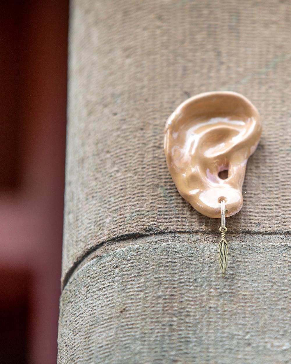 Close-up of an ear made of ceramic sits mounted on a house wall.