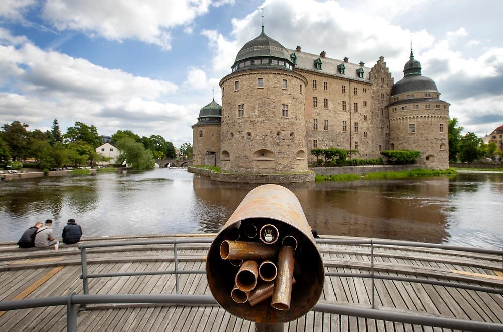 A metal sculpture is placed on the piers along Storgatan, in front of Örebro Castle. The sculpture consists of metal tubes welded together and resembles a large pair of binoculars looking out over the water and the castle. A close-up of the sculpture at the bottom of the picture, Örebro Castle can be seen in the background