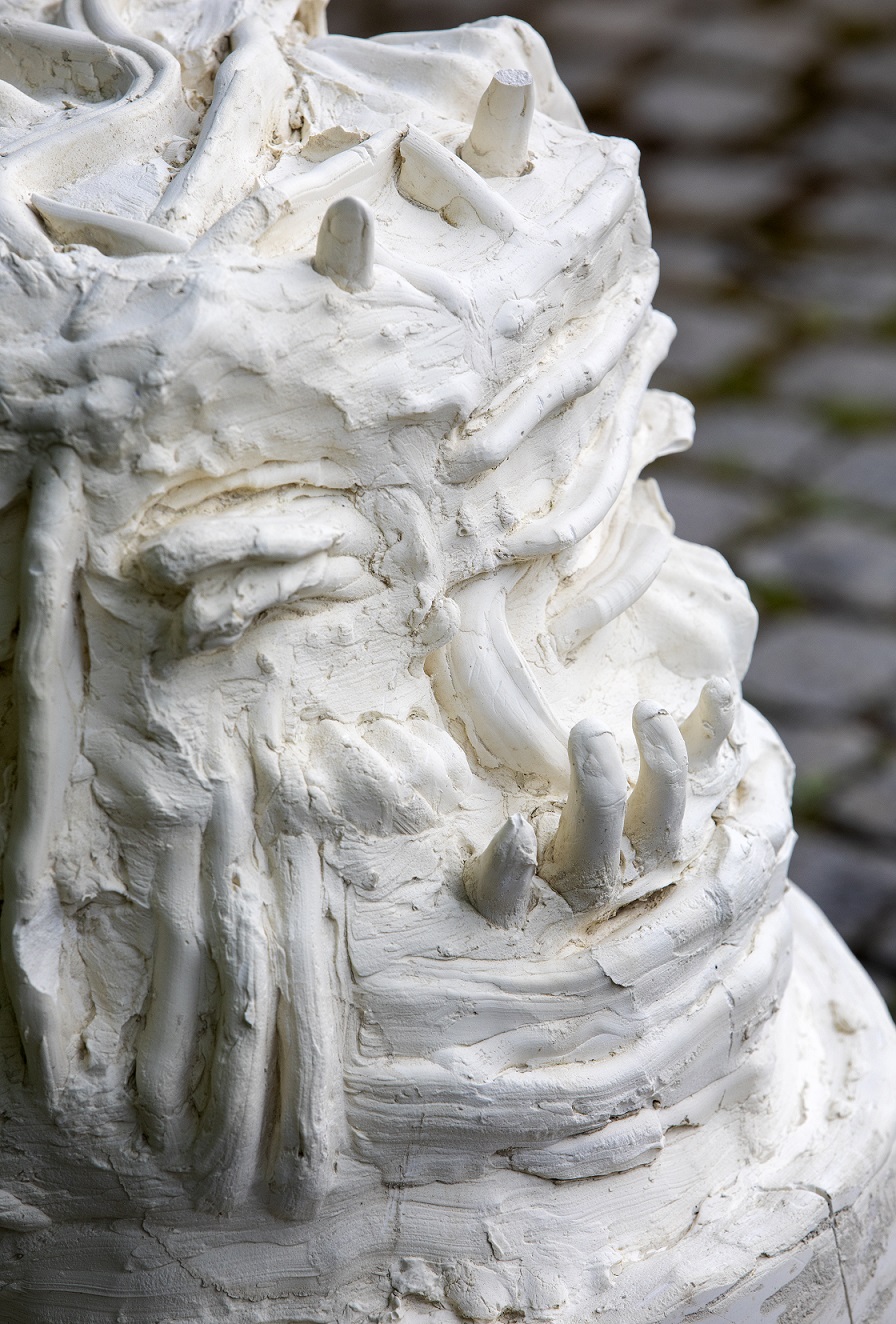 Close-up of a concrete sculpture where a dialogue has taken place in sign language. Finger movements are visible in the concrete and some fingers stick out of the sculpture.