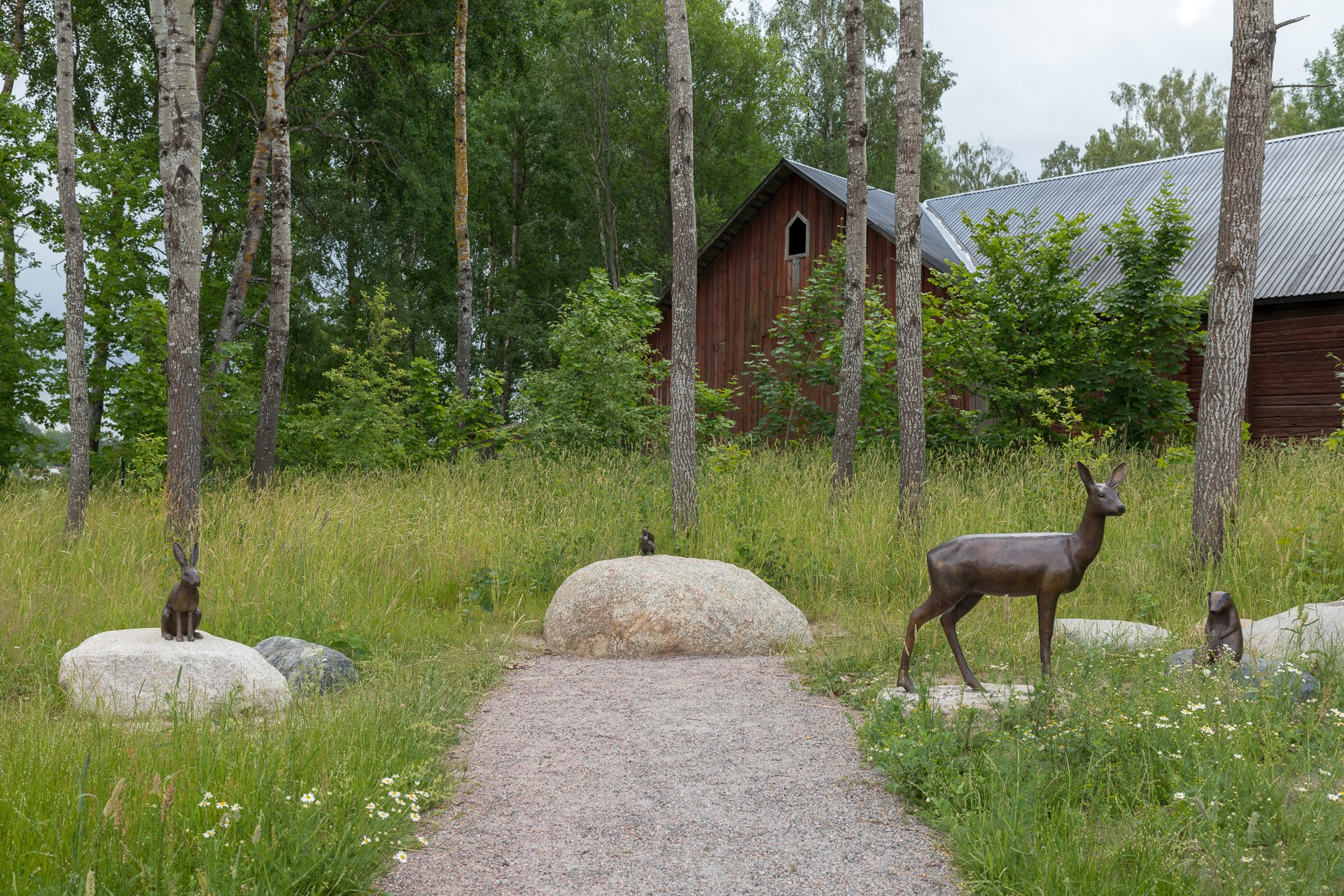 Skulpturer föreställande ett rådjur, kanin osv placerade i en skogsglänta. 