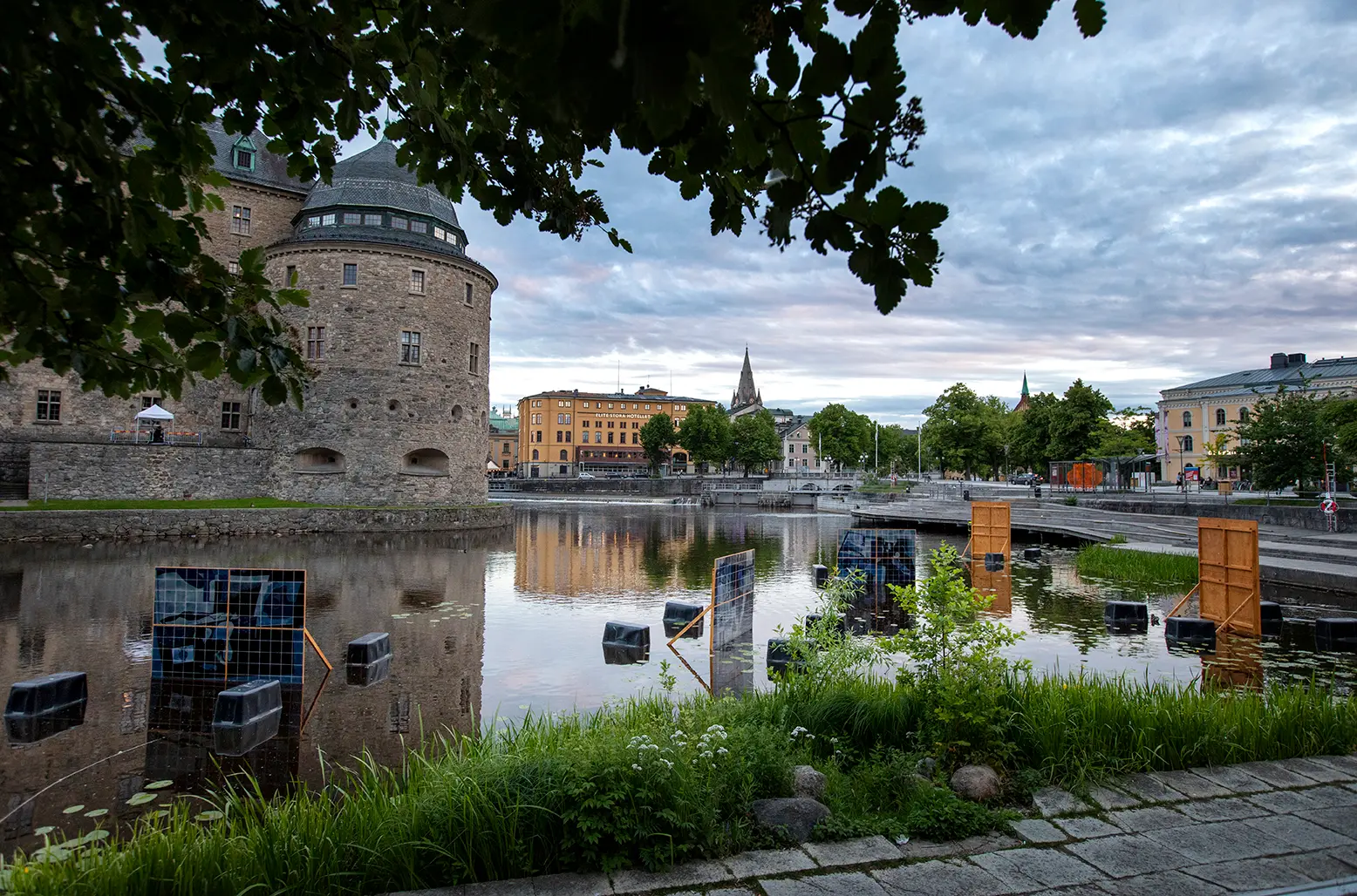 Overview of paintings made of ceramic tiles in shades of blue that are placed in the water around Örebro Castle.